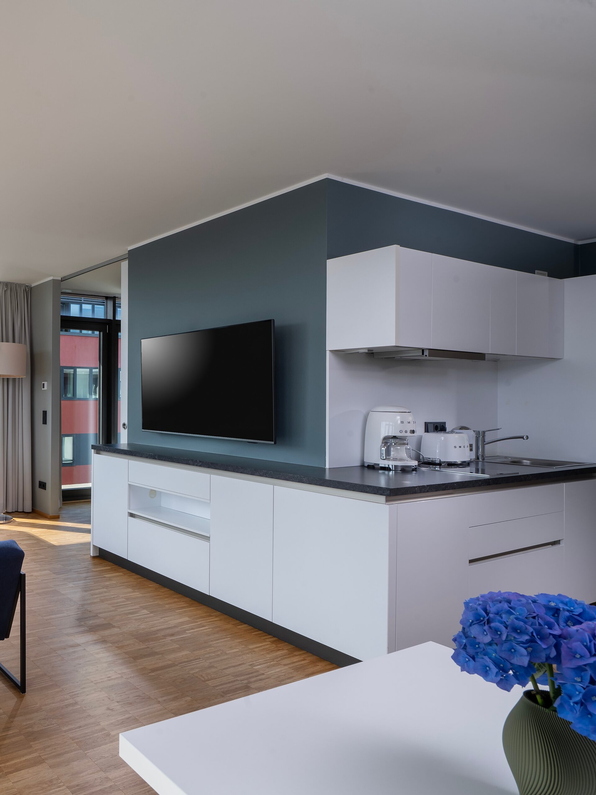 Moderne Küchenzeile mit TV und Essbereich im Apartment des Wavehotel Potsdam