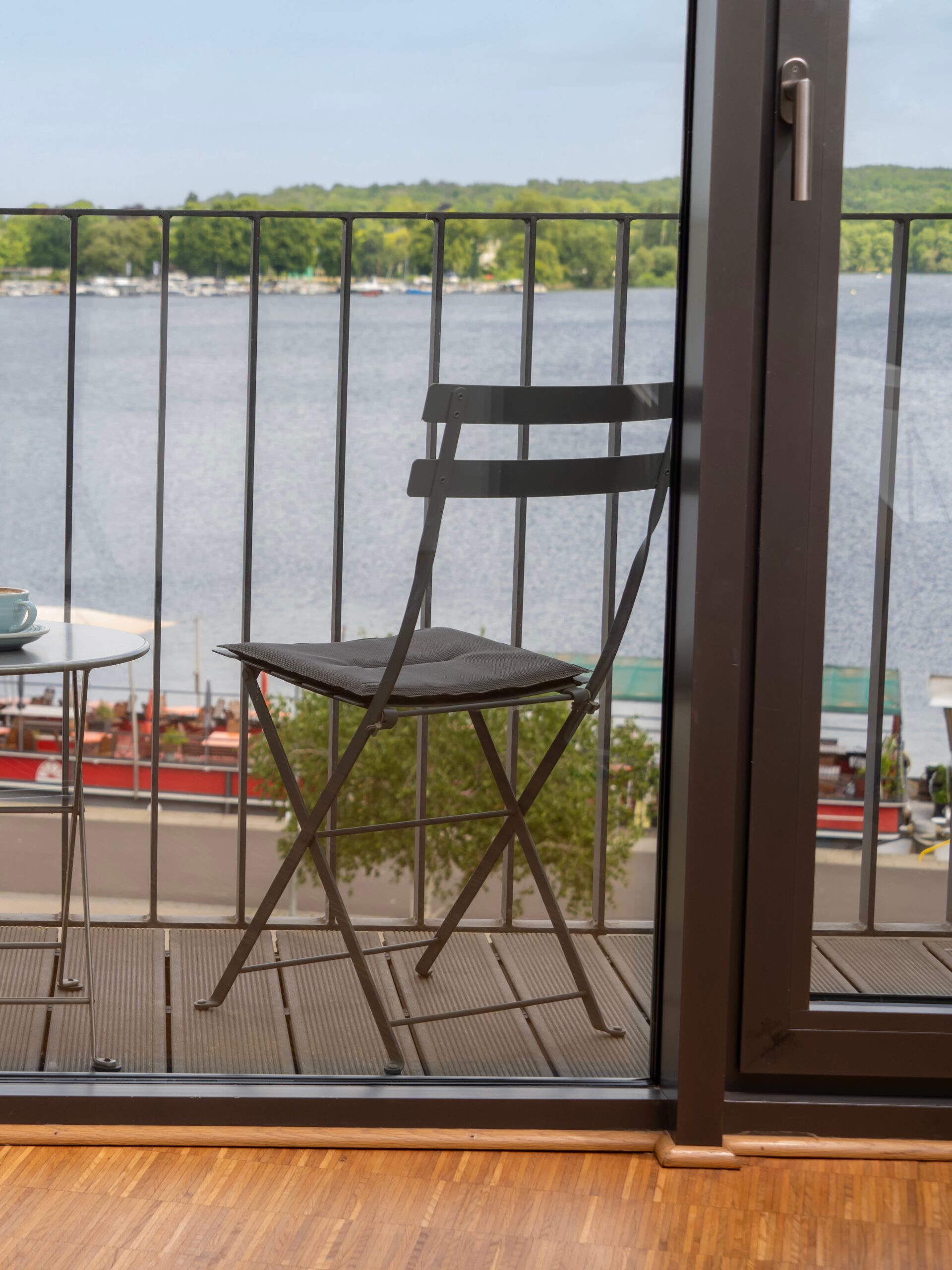 Balkon mit Stuhl und Tisch im Wavehotel Potsdam mit Blick auf die Havel