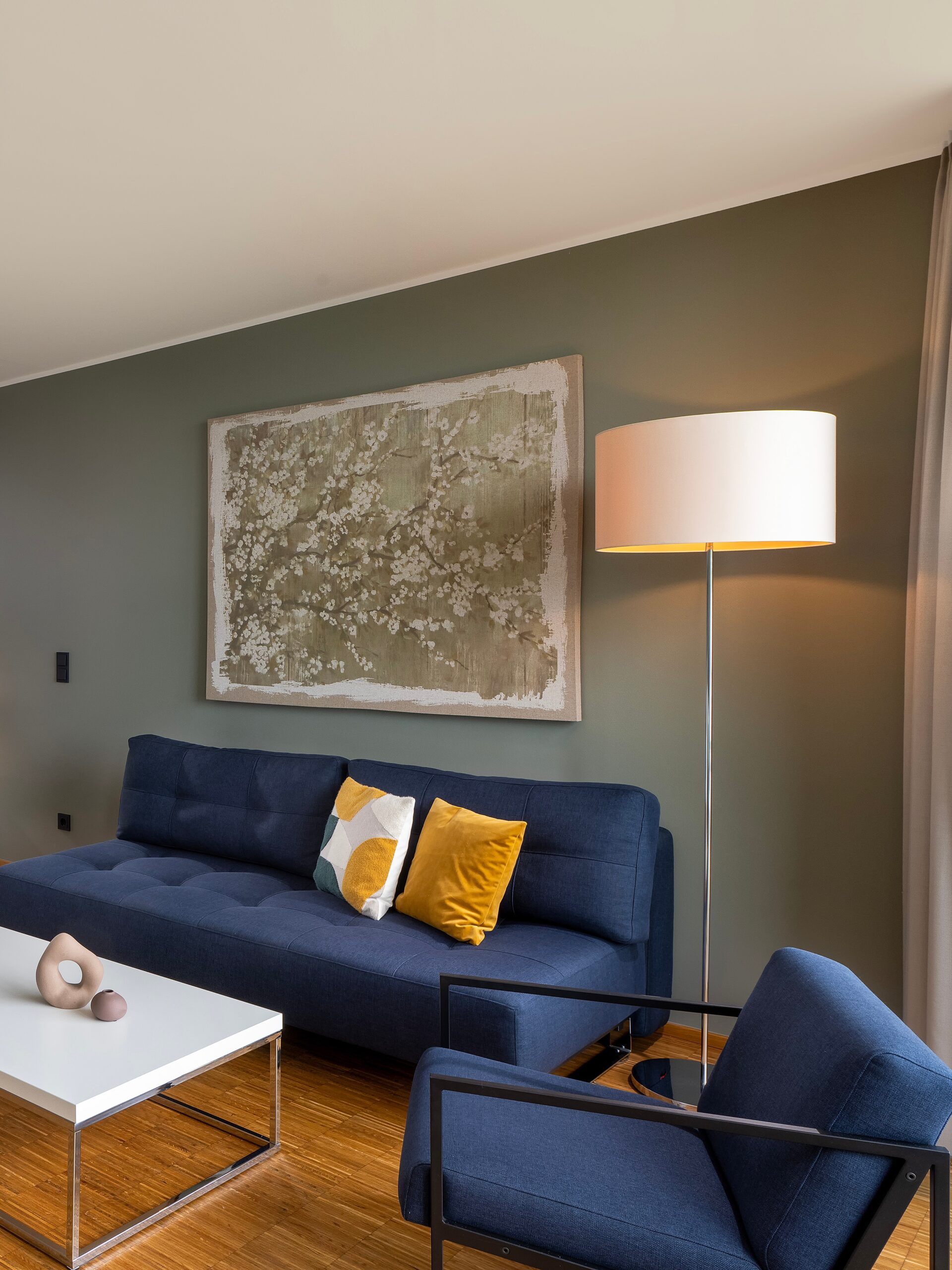 Gemütlicher Wohnbereich im Wavehotel Potsdam mit Designsofa, Stehlampe und moderner Wandkunst