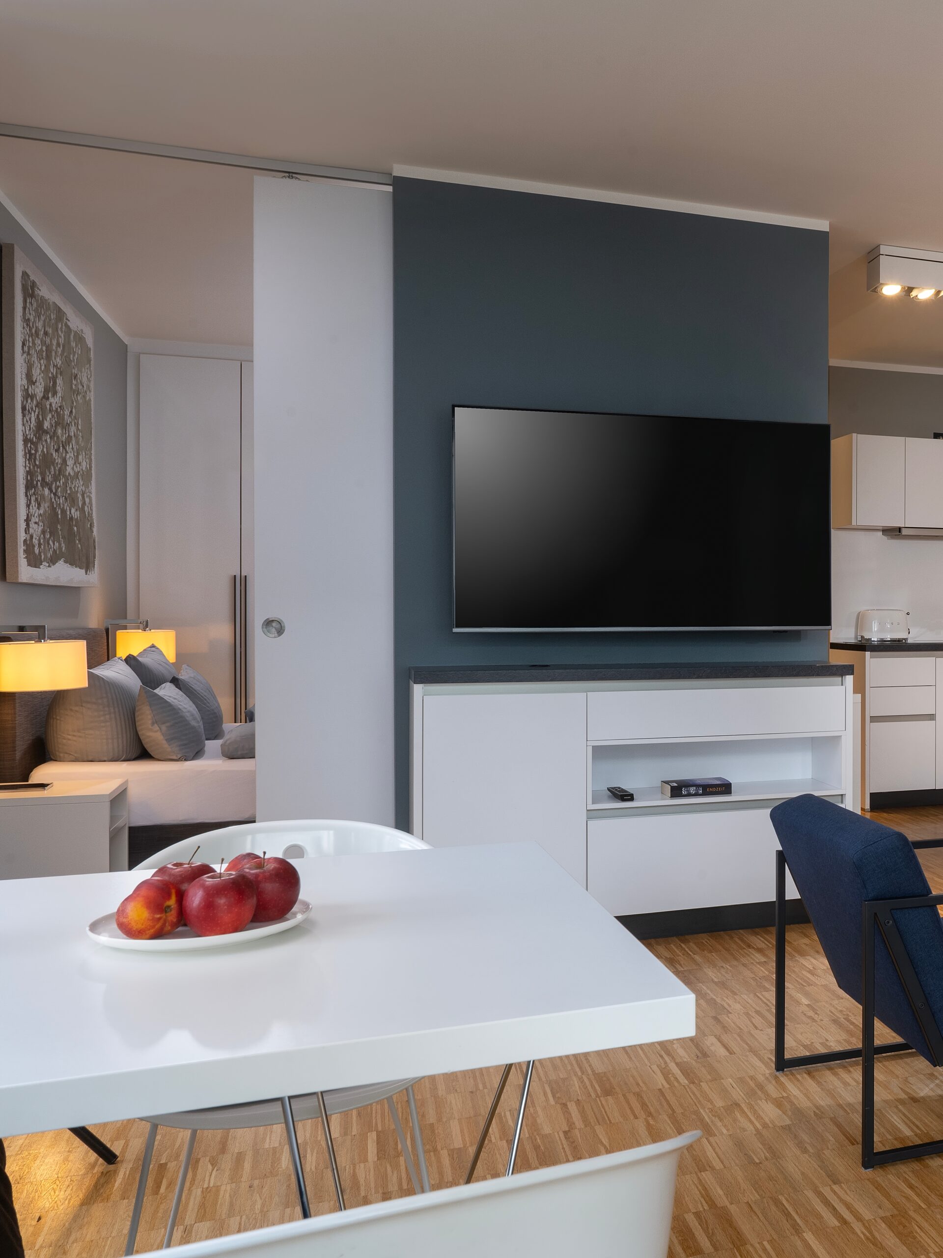 Modernes Hotelapartment im Wavehotel Potsdam mit Esstisch, Flachbild-TV und Blick ins Schlafzimmer